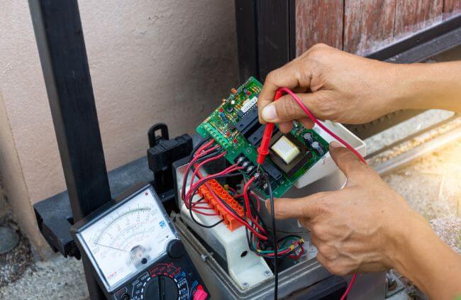 Automatic gate maintenance technician checking gate control board and wiring during repair service by Auto Gate Guys Perth.
